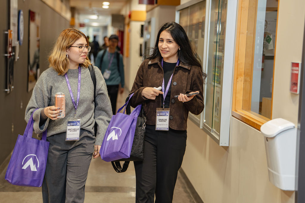 Two attendees walking with purple CDM Summit bags