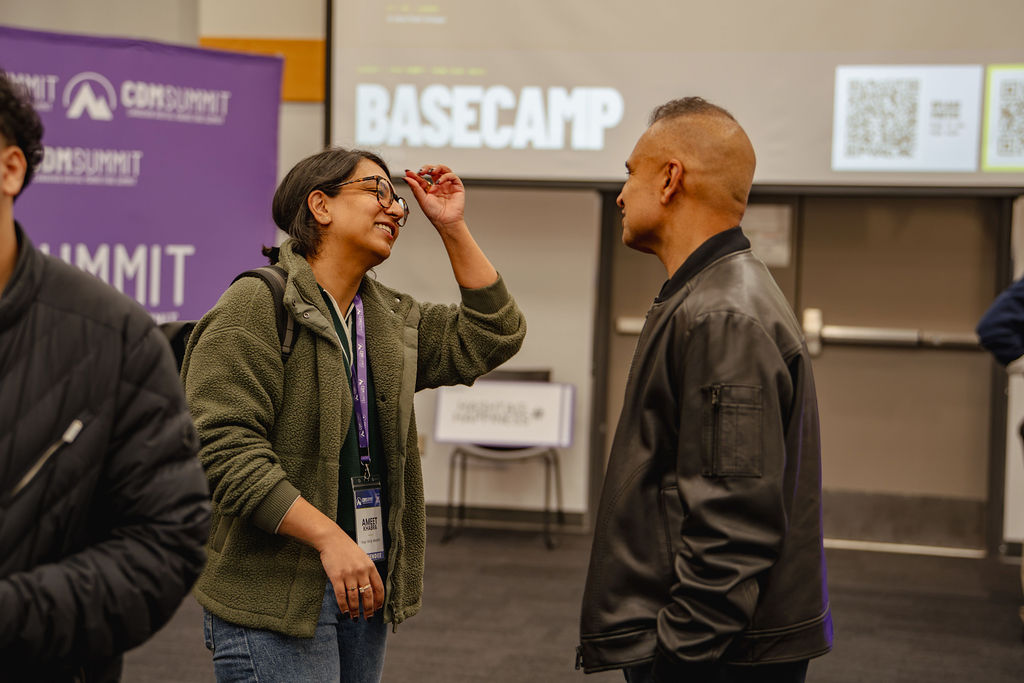 Two attendees talking with Basecamp displayed behind them