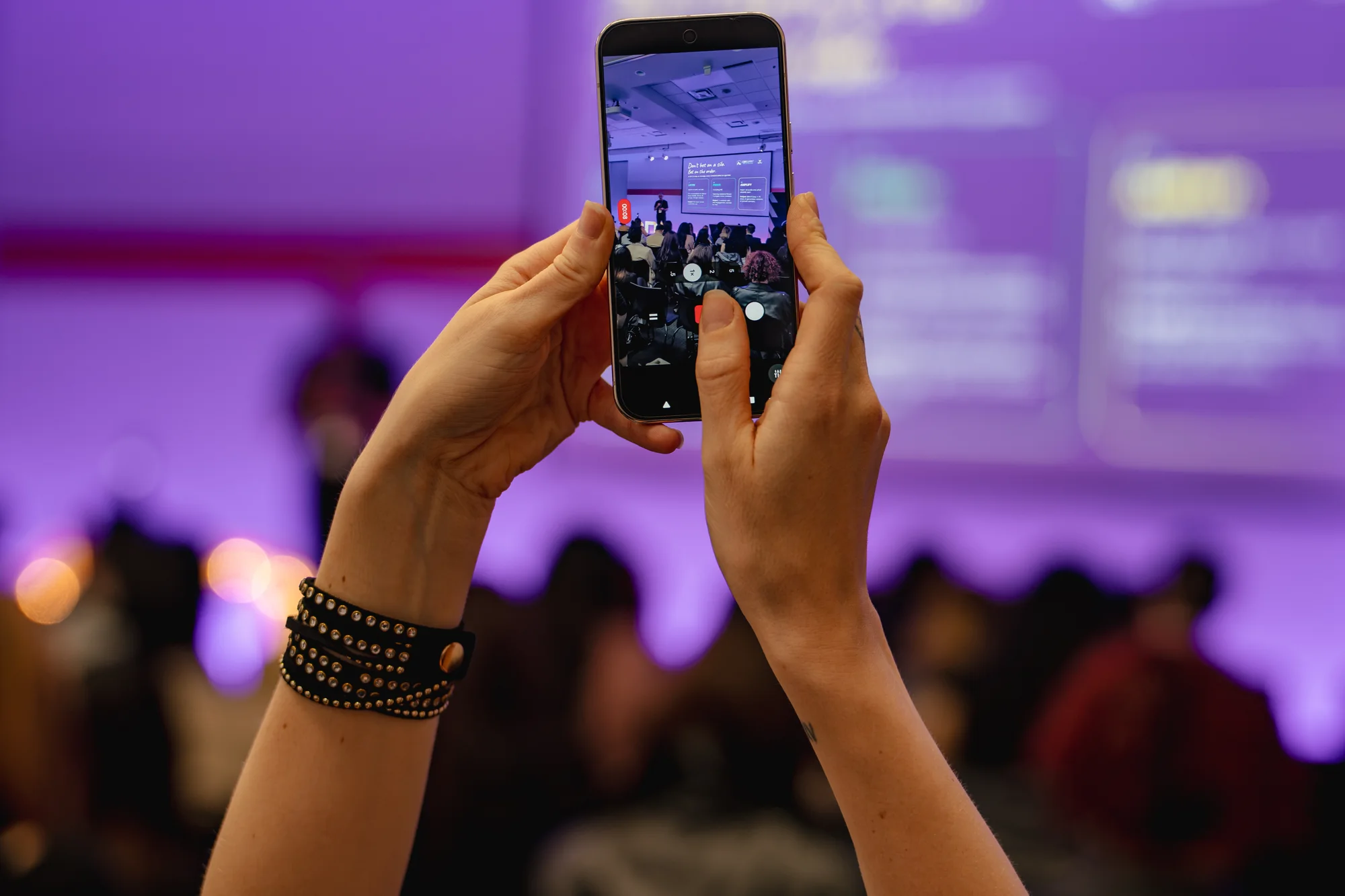 Attendees holding phones up to capture the stage.