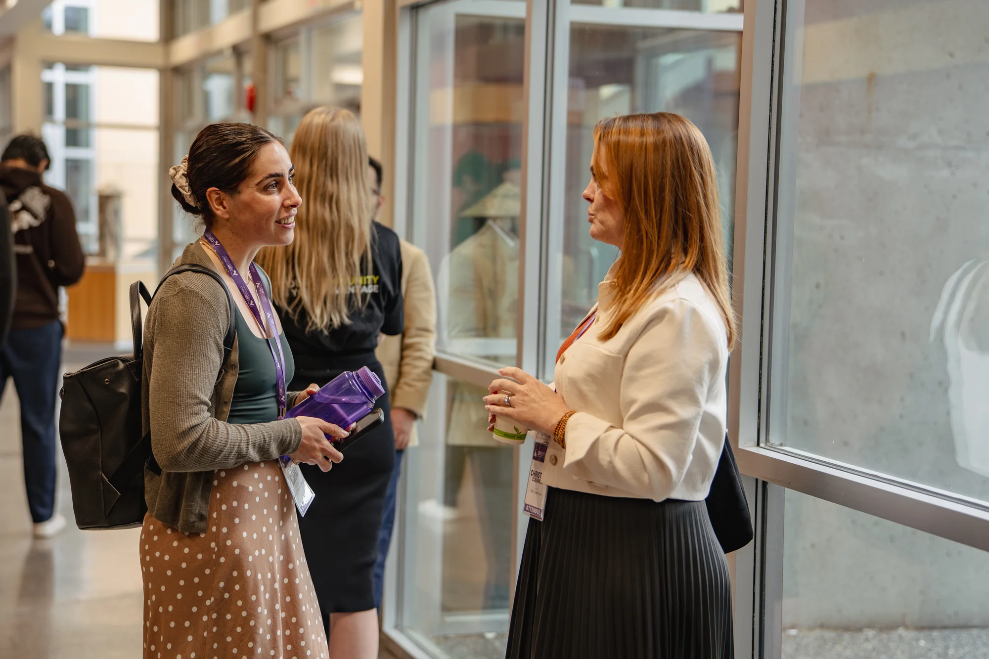 Two attendees talking beside a hallway window at CDM Summit Fraser Valley 2026