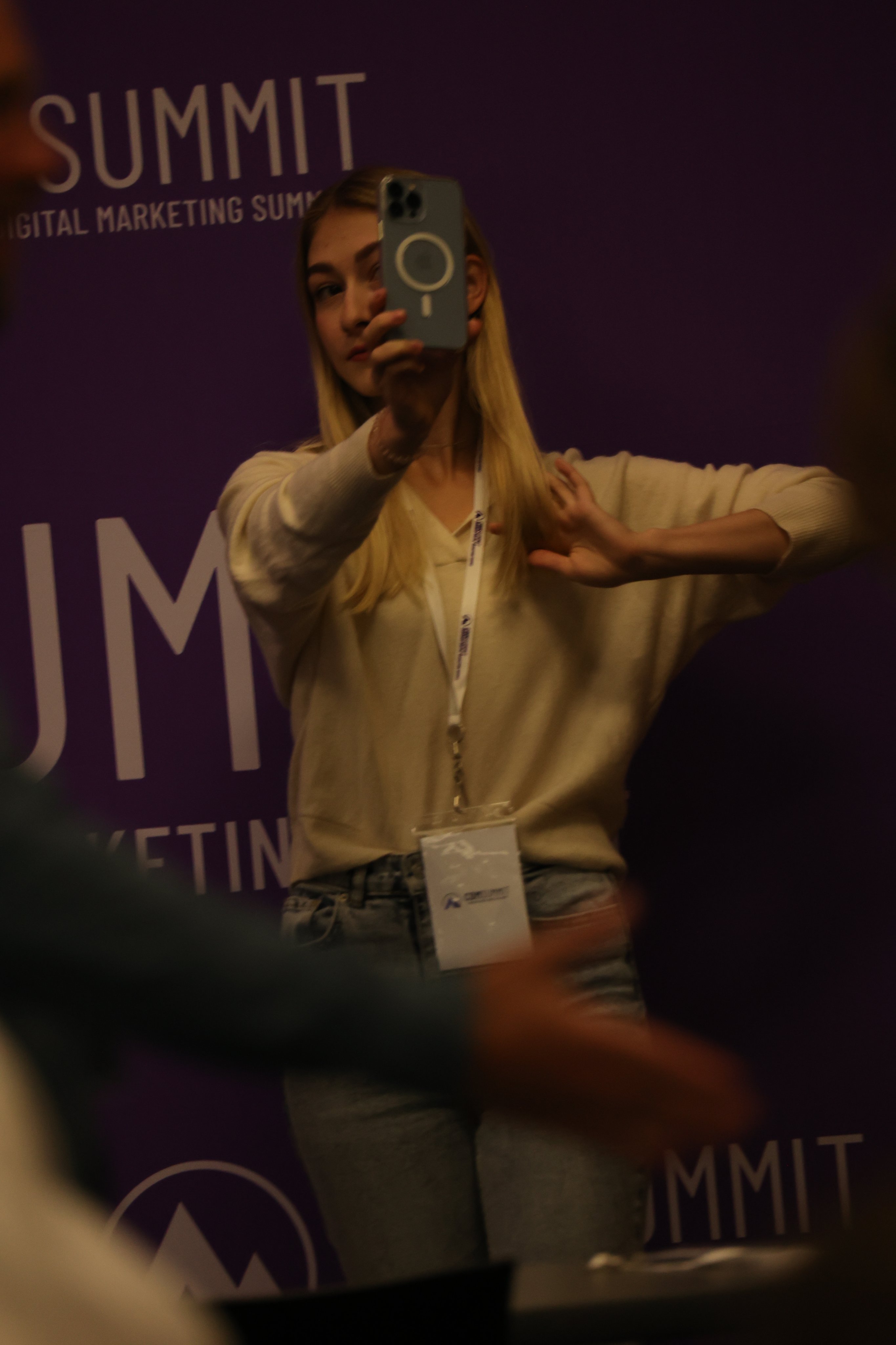 An attendee taking a selfie at the purple summit backdrop
